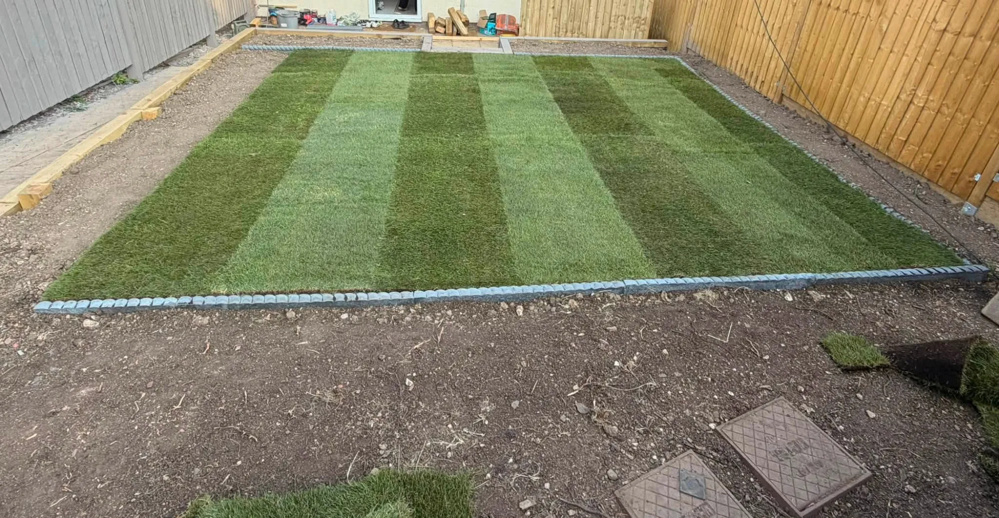 After: fresh striped turf laid with stone edging